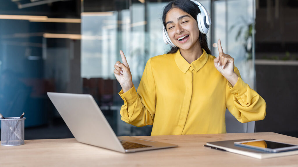 Ratgeber Kündigung - bild kopfhoerer am arbeitsplatz 1 Ein junge Frau mit Kopfhörern und Laptop hört während der Arbeit Musik.