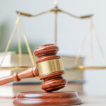 Bildlich ist ein Gerichtsurteil dargestellt, mit dem Richterhammer. Es geht um die Anrechnung der Krankheitstage eines Arbeitnehmers nach dessen Versetzung.