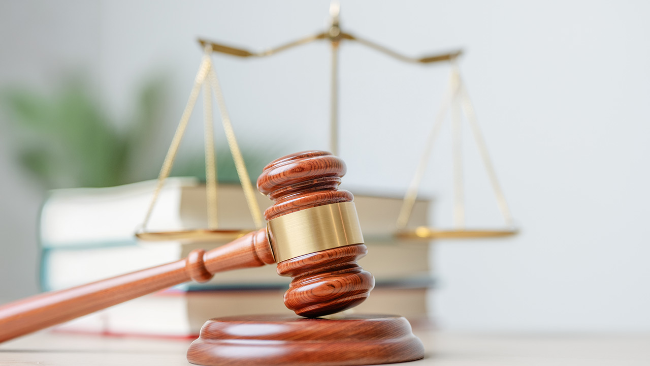 Bildlich ist ein Gerichtsurteil dargestellt, mit dem Richterhammer. Es geht um die Anrechnung der Krankheitstage eines Arbeitnehmers nach dessen Versetzung.