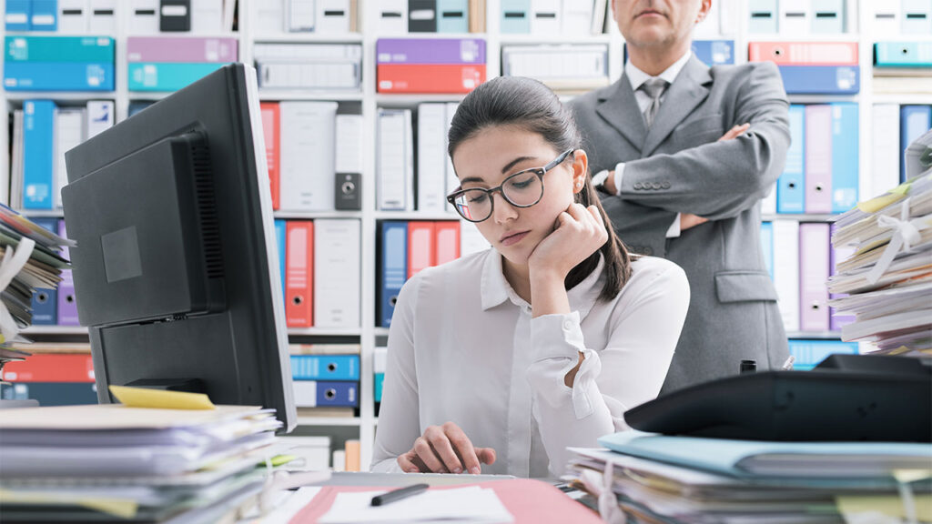 Mikromanagement im Job: Wenn übertriebene Kontrolle gute Mitarbeiter vertreibt - bild mikromanagement im job 1 Eine junge Angestellte wird von ihrem Vorgesetzten kontrolliert.