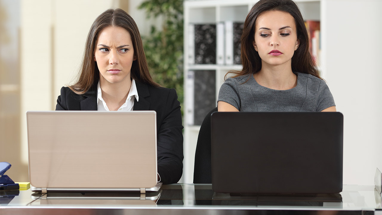 Zwei Frauen mit Laptop vertrauen sich nicht. Verbale No-Gos am Arbeitsplatz