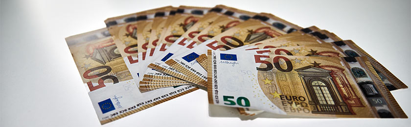 Mehrere 50€ Scheine auf einen Tisch liegend, die man nach vielen Jahren der Betriebszugehörigkeit bei einem Ausscheiden als Abfindung erhalten kann.