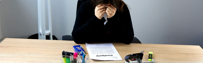 Eine Frau weint im Büro, weil ihr in der Probezeit gekündigt wurde.
