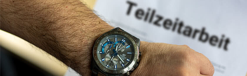 Eine Armbanduhr mit einem Teilzweivertrag im Hintergrund.